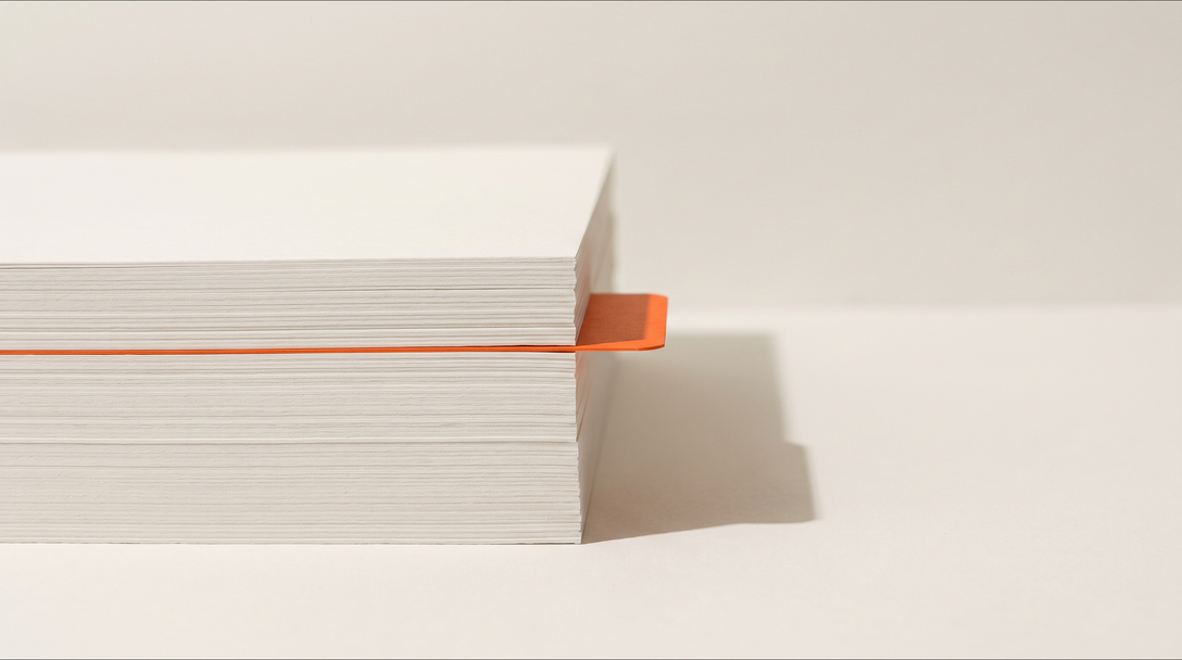 Tall stack of blank white paper with a single orange divider tab at just past the halfway point