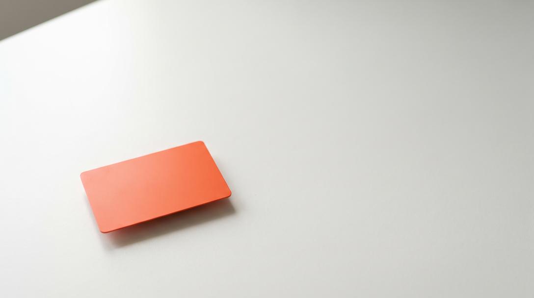 Single plain orange keycard alone on a wide empty off-white surface