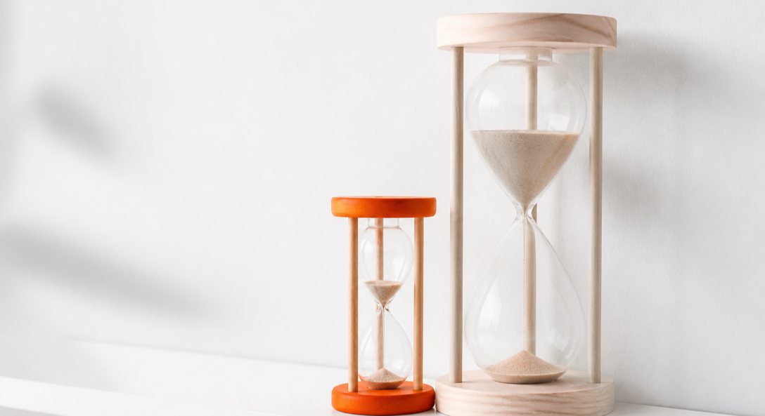 A small orange hourglass running fast beside a tall wooden hourglass running slowly