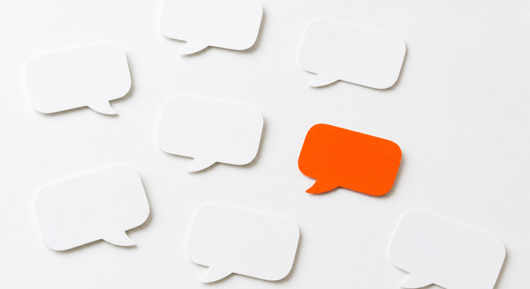 White paper speech bubbles on a table with one orange speech bubble